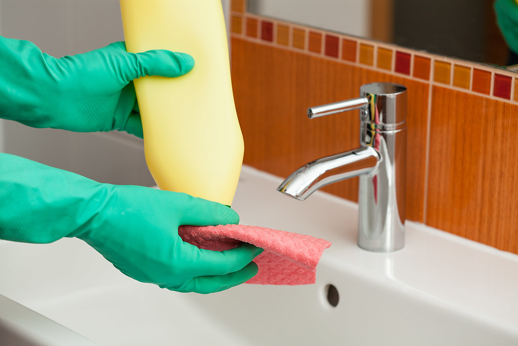 Gloved hands cleaning a sink